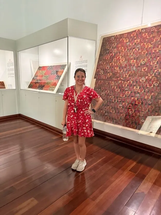Ana Masias, artista plástica peruana en la sala Vestimentas del Antiguo Perú, frente a textiles prehispánicos